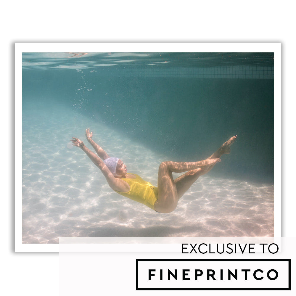 A person wearing a yellow swimsuit floats gracefully underwater with arms stretched upward and legs bent. The water around them is clear, and sunlight creates shifting patterns on the pool floor. The text "EXCLUSIVE TO FINEPRINTCO" is seen at the bottom, signifying its status as one of their fine art prints titled "Halcyon Daze 1" by Francesca Owen.