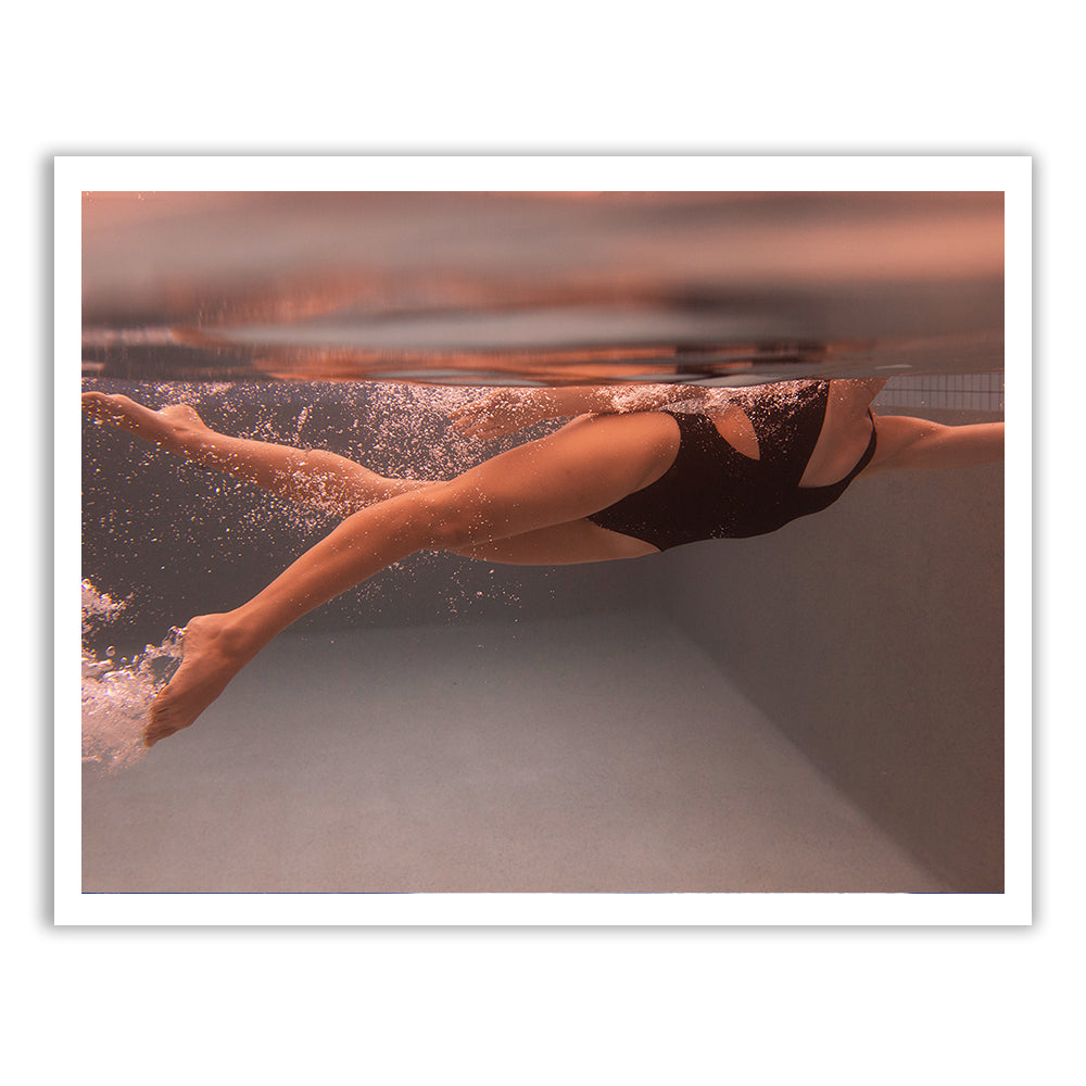 An underwater photo titled "Self Reflection 06" by Francesca Owen captures a swimmer in a black swimsuit mid-stroke, with only the lower body visible. The swimmer's legs are extended, and bubbles trail behind, creating a dynamic sense of movement in the clear water—a perfect moment for custom framing or fine art prints to preserve its beauty.