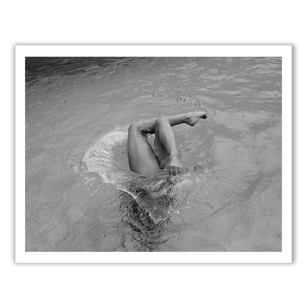 Self Reflection" by Francesca Owen depicts a black and white photograph of a person partially submerged in water, captured mid-dive with their legs and feet emerging from the surface, creating a splash. The water's ripples and motion are artfully preserved around their body. This fine art print is created using archival pigments and includes a certificate of authenticity.